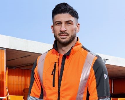 A waste management employee wears an orange work jacket.